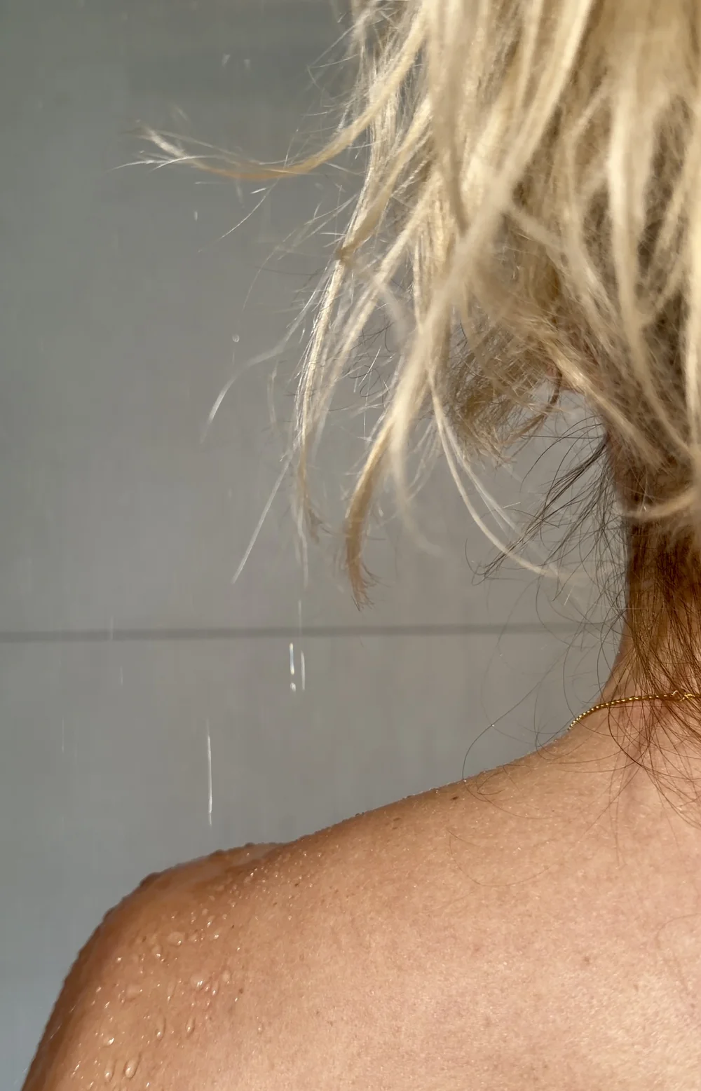 Eine kalte Dusche nach der Sauna, mit Wassertropfen auf einer Schulter.